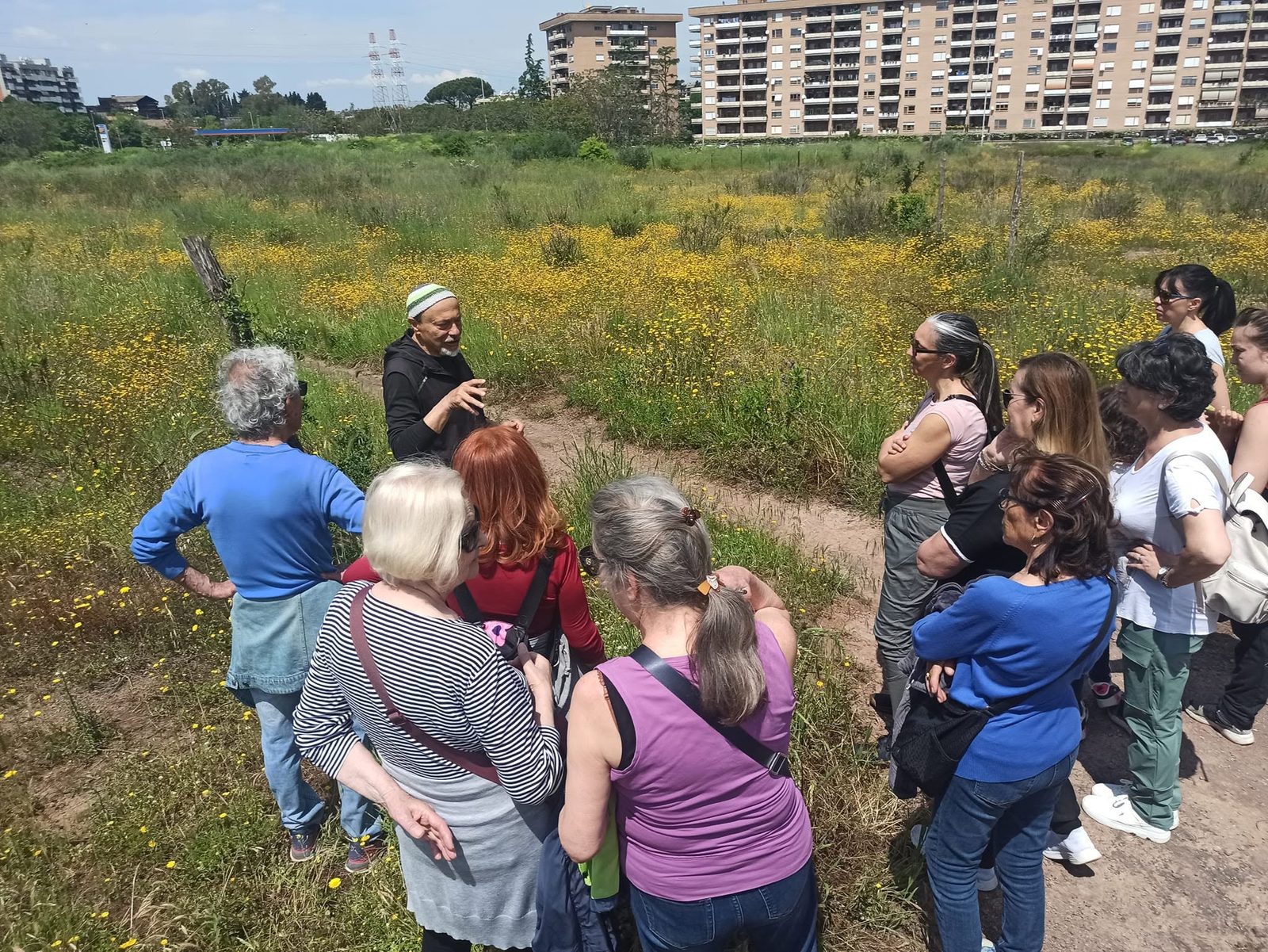 Il gruppo del cammino econaturalistico ascolta la guida tra i prati fioriti